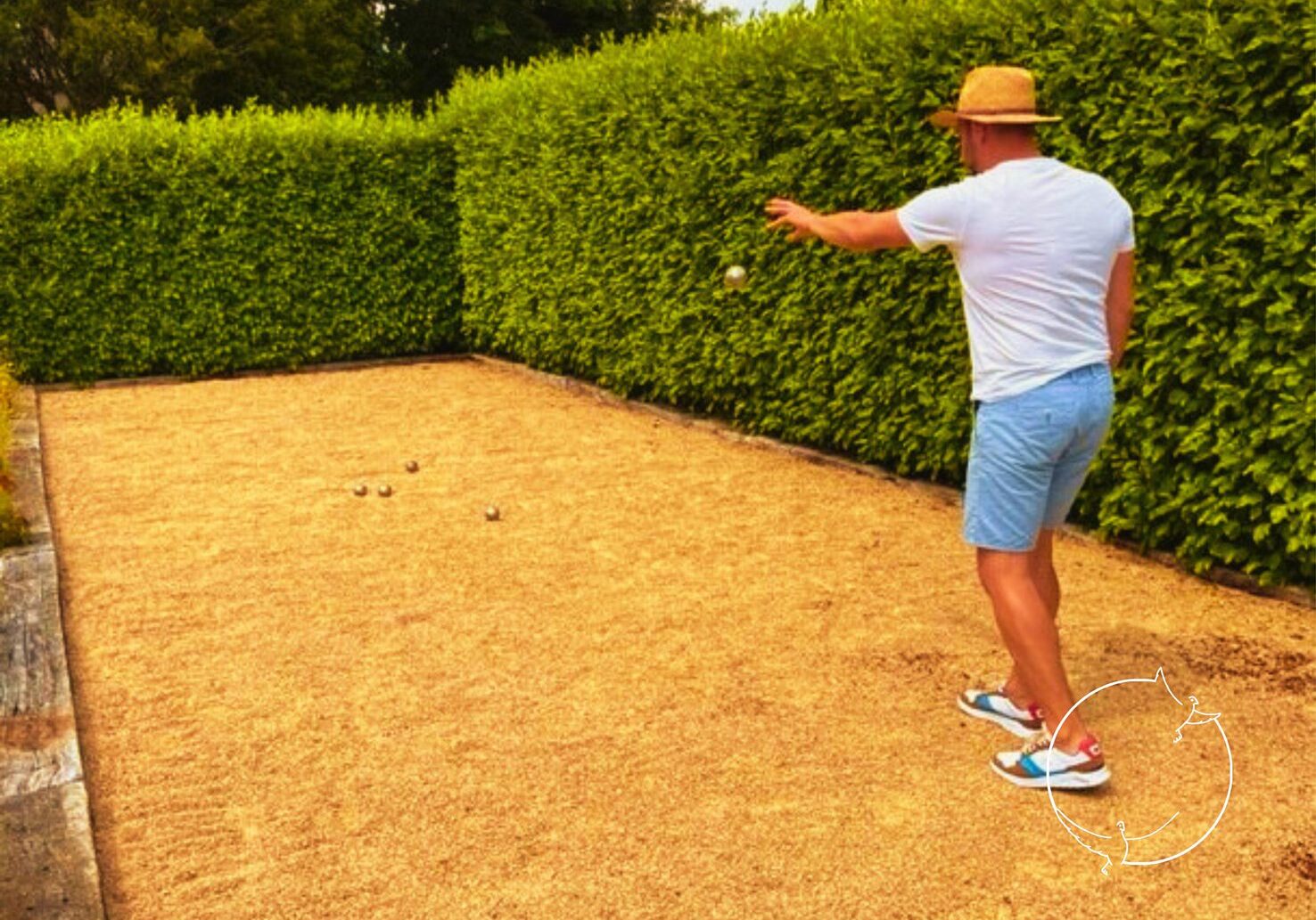 Dave is the owner of Kergudon and is playing petanque or Boules on the boules pitch surrounded by a beautiful green hedge